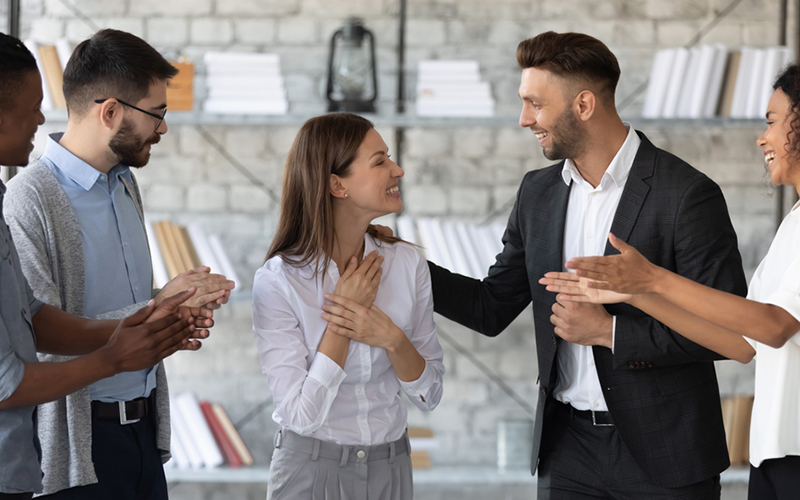 Smiling woman being congratulated by colleagues