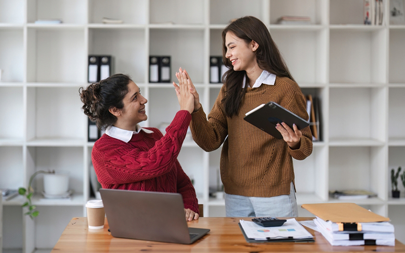 Two smiling women giving each other a high-five